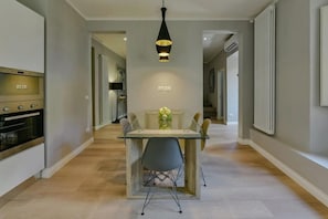 A modern kitchen with a glass-top dining table, a black pendant light, and a built-in oven. - Ponte Vecchio Deluxe (Florence)