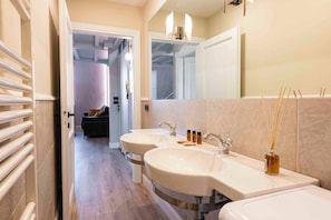 A modern bathroom with two sinks, a large mirror, and a hallway leading to a living area. - Giglio di Firenze (Florence)