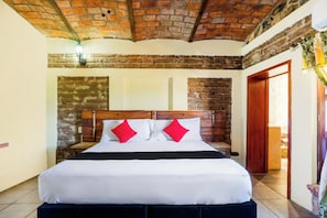 A hotel room with a brick ceiling, a wooden headboard, a large bed with white bedding and red pillows, and a wooden nightstand. - Collection O Hotel Monte Agave (Tequila)