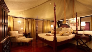 Ein Bett mit Himmelbett, ein Holzkonsolenmöbel, ein Stuhl und ein Nachttisch mit Lampe.