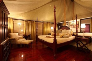 A four-poster bed with a canopy, a wooden dresser, a chair, and a bedside table with a lamp. - Tuli Tiger Corridor (Barghat)