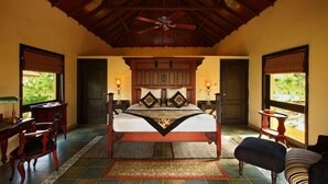 A spacious bedroom with a large bed, wooden headboard, two bedside tables with lamps, a ceiling fan, and a view of greenery outside. - Tuli Tiger Corridor (Barghat)