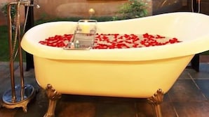 A bathtub filled with red rose petals and a candle, with a metal stand beside it. - Tuli Tiger Corridor (Barghat)