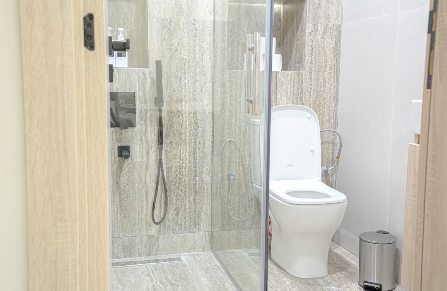 Ein modernes Badezimmer mit einer Duschkabine aus Glas, einer weißen Toilette und einem Mülleimer.