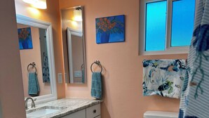 Ein Badezimmer mit Marmorwaschbecken, Toilette, Mülleimer und einer blauen Fußmatte.