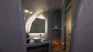 Un baño con lavamanos blanco, espejo y planta en maceta.