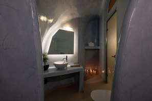 Ein Badezimmer mit einem weißen Waschbecken, einem Spiegel und einer Zimmerpflanze.