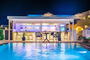 A poolside bar area with seating and a bar counter. - Santoterra Antigua Luxury Suites (Santorini)