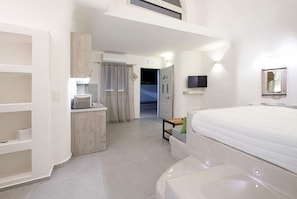Ein Hotelzimmer mit einem Bett, einem Schreibtisch mit einer Mikrowelle, einem Kleiderschrank, einem Spiegel und einem Fernseher.