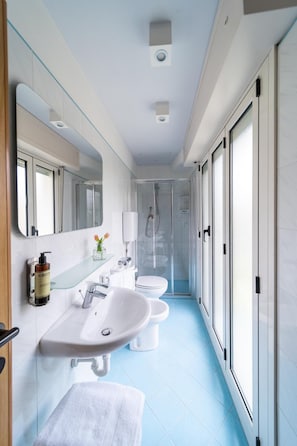 A modern bathroom with a glass shower enclosure, a white sink, and a toilet. - Hotel Ancora (Rimini)