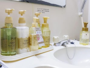 Ein Badezimmer mit einem Waschbecken, einem Spiegel und mehreren Flaschen ZIRA Duschgel.