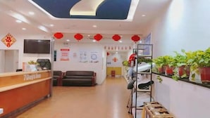Un'area della reception di un hotel, con scrivania, posti a sedere e una televisione a parete.
