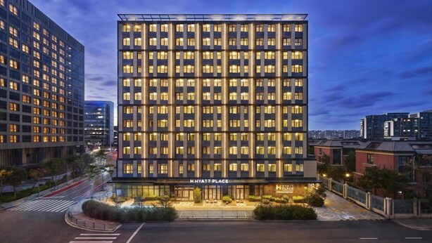 Ein mehrstöckiges Hotel mit moderner Fassade, beleuchteten Fenstern und freiem Blick auf die Straße.