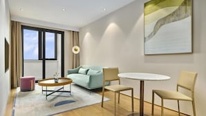 Ein modernes Hotelzimmer mit einer Couch, einem runden Tisch und zwei Stühlen.