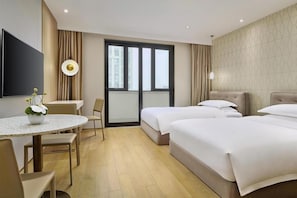 A hotel room with a bed, a desk, a chair, a TV, and a window.