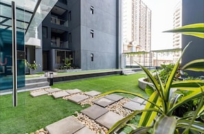 A modern building with a rooftop garden, featuring a pathway, greenery, and a glass facade. - Lovely 1-bedroom apartment in Kilimani oak residence perfect for your stay (Nairobi)
