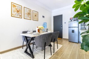 Uma área de refeições com uma mesa posta para quatro pessoas, um bebedouro e uma geladeira.