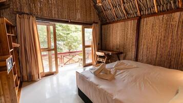 Una habitación con una cama, un escritorio de madera y un ventanal amplio.