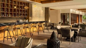 A bar area with a long counter, multiple stools, and a seating area with tables and chairs.
