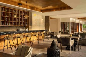 A bar area with a long counter, multiple stools, and a seating area with tables and chairs.