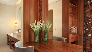 A wooden dining table with two green vases, a mirror, and a wooden cabinet with a decorative panel.