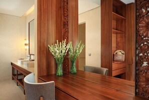 A wooden dining table with two green vases, a mirror, and a wooden cabinet with a decorative panel.