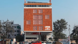 Ein Hotel mit roter Backsteinfassade, zahlreichen Fenstern und einem Schild mit der Aufschrift 'Ira Orchid Hotels'.
