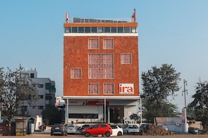 Um hotel com fachada de tijolos vermelhos, várias janelas e uma placa com o nome 'Ira Orchid Hotels'.