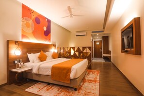 Ein Hotelzimmer mit Bett, Nachttisch und einem an der Wand befestigten Fernseher.
