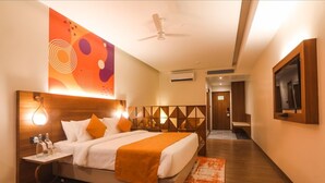 Ein Hotelzimmer mit Bett, Nachttisch und einem an der Wand befestigten Fernseher.