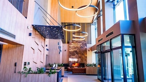 Un moderno vestíbulo de hotel con chimenea, paneles de madera y una partición de vidrio.