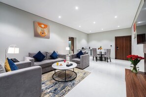 Una sala de estar moderna con sofás grises, una mesa de centro y un comedor con una mesa y sillas.