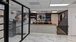 A lobby with a reception desk, a glass door entrance, and an ATM machine. - Hotel Cartersville, GA (Cartersville)