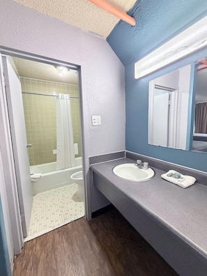 Un baño con ducha, lavamanos y espejo.