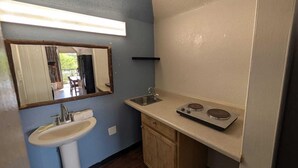 A compact kitchen with a sink, countertop, and a stove. - Hotel Cartersville, GA (Cartersville)