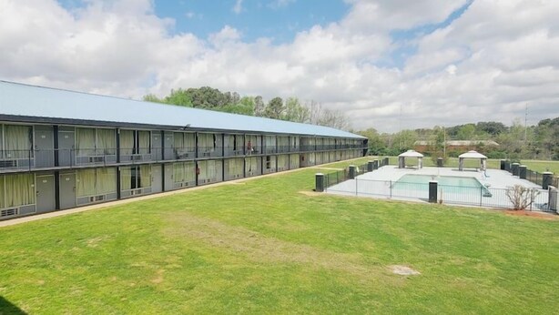 A hotel with a long corridor, a swimming pool, and a fenced area. - Hotel Cartersville, GA (Cartersville)