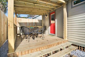 A wooden deck with a table and chairs, a red door, and a wooden fence. - Callahan`s Hideaway on Marine (Mobile)