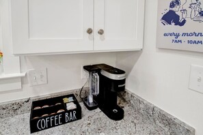 A kitchen with a coffee maker, a coffee bar sign, and a wall clock. - Callahan`s Hideaway on Marine (Mobile)