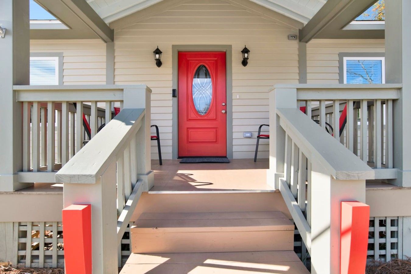A front porch with a red door, two steps leading up to it, and a small porch area with a chair.