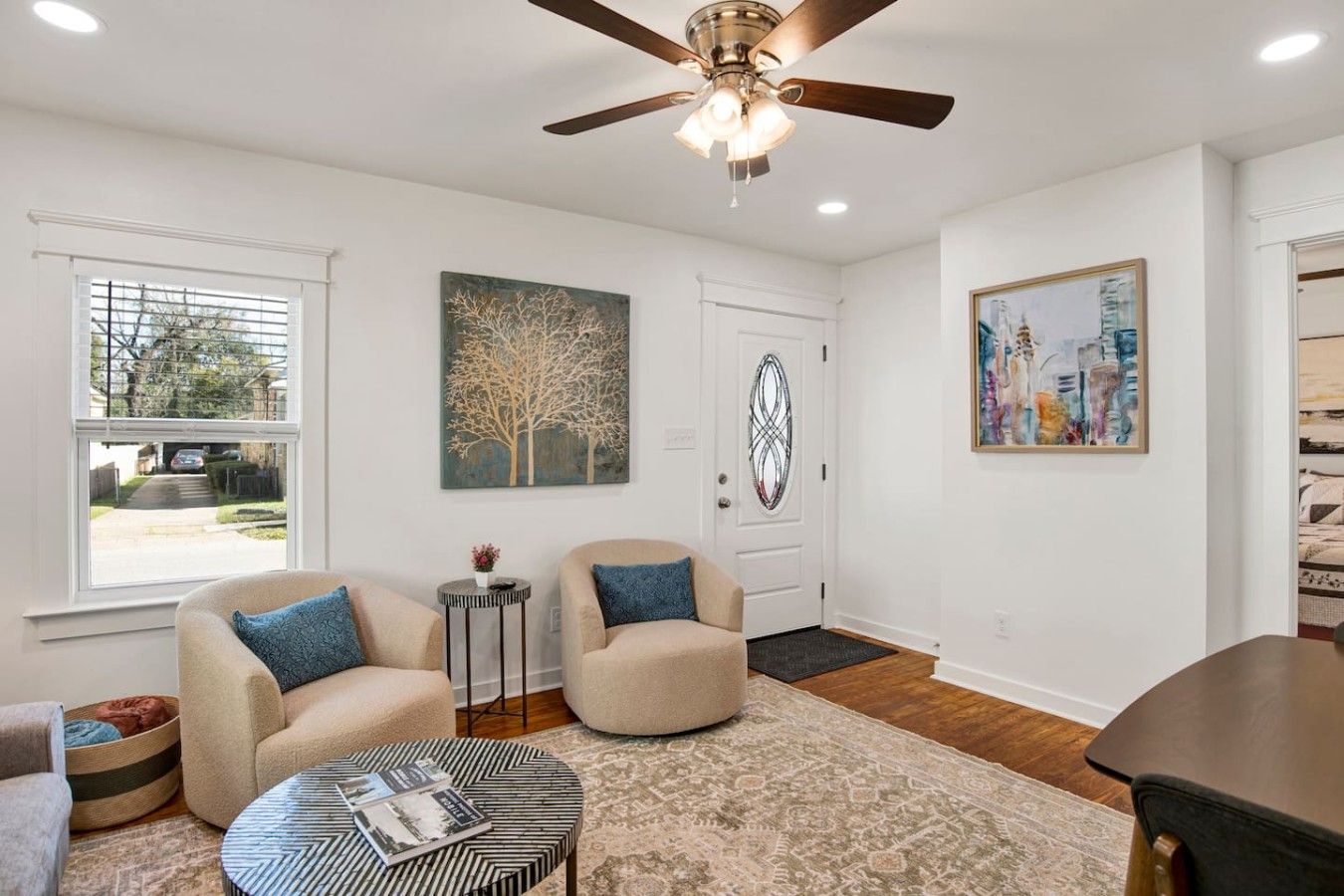 A living room with two sofas, a coffee table, a ceiling fan, and artwork on the walls.