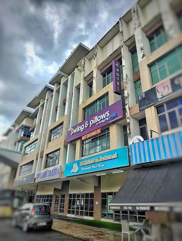 Un edificio de varios pisos con diversos establecimientos comerciales, incluyendo un hotel, un restaurante y una tienda llamada 'Swing & Pillows'.
