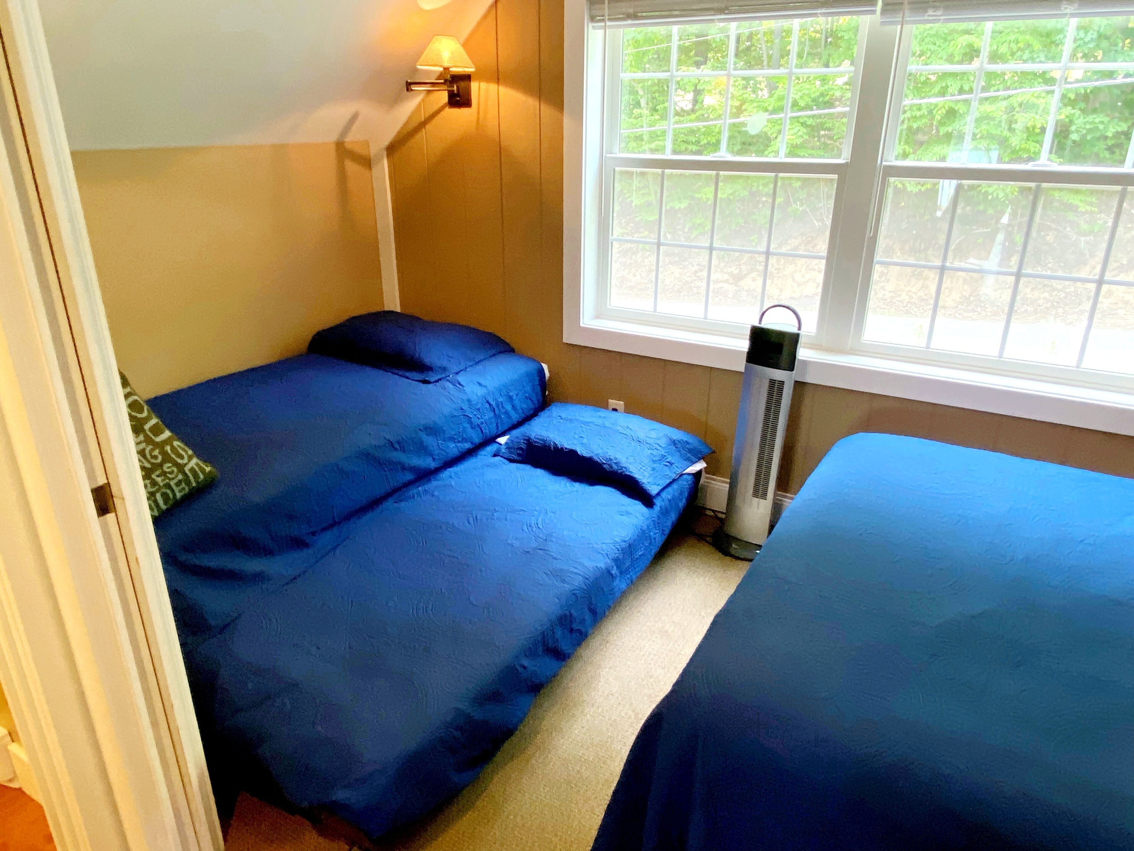 Ein Zimmer mit zwei Betten, einem Fenster mit Blick auf Grünflächen und einem Wandheizkörper.
