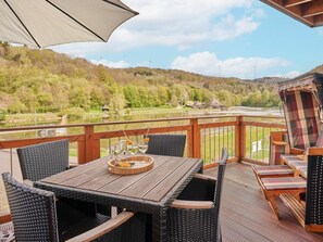 A wooden deck with wicker furniture and a table set with glasses and a tray. - Holiday Apartment Mila OG (Rieden)