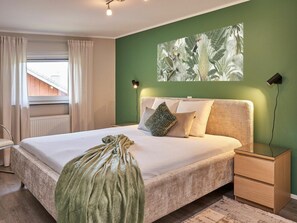 A bedroom with a bed, bedside table, and a wall-mounted artwork. - Holiday Apartment Mila OG (Rieden)