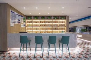 Un área de recepción con mostrador, taburetes de bar y estantes llenos de botellas.