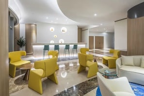 Una hall moderna con una reception, sedute gialle e bianche e un pavimento in marmo.