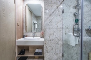Un bagno con lavabo in marmo, cabina doccia in vetro e porta asciugamani.