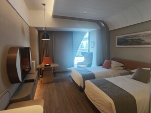 Una habitación de hotel moderna con una cama, un escritorio, una silla y un ventanal grande.