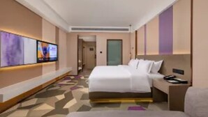 A hotel room with a bed, a bedside table, a TV mounted on the wall, and a carpeted floor. - Lavande Hotel (Zhuhai)