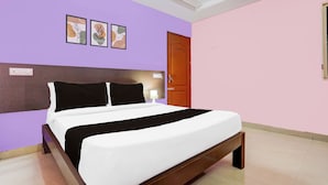 A hotel room with a bed, a wooden headboard, a door, and a wall with three framed pictures. - OYO Hotel O Karakambadi Near Alipiri (Tirupati)